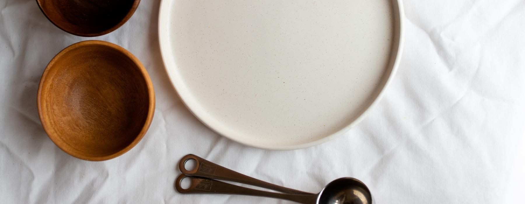 a white plate with a brown bowl and a spoon on it